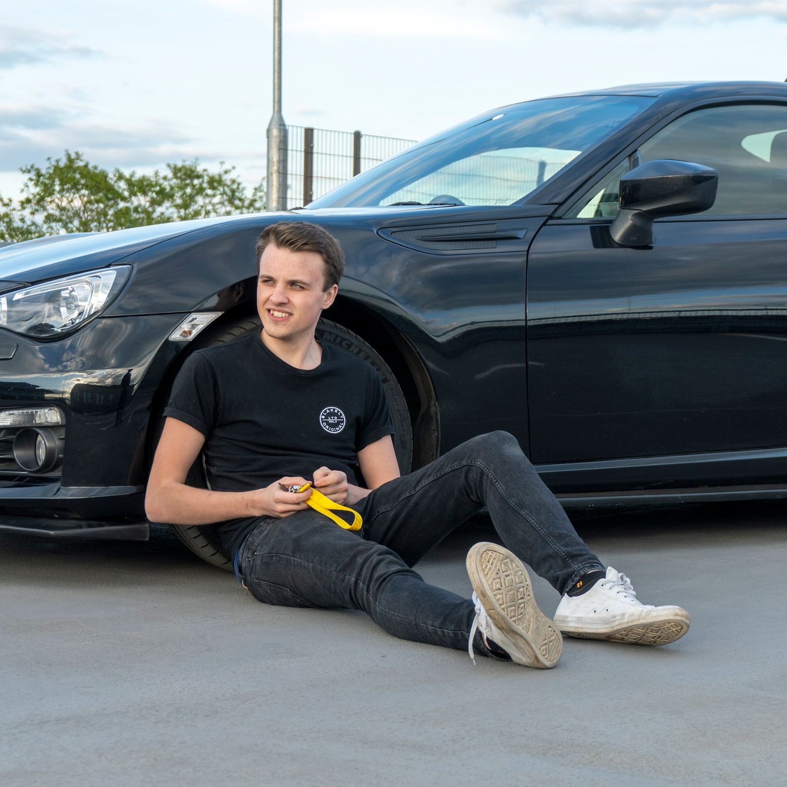 Chris Cousall sitting beside a car.
